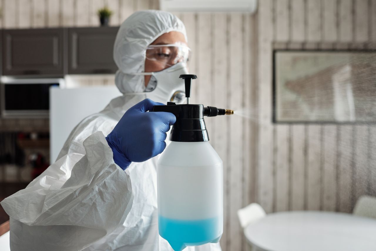 Professionnel entièrement équipé désinfectant un espace intérieur à l’aide d’un pulvérisateur pour prévenir la COVID-19.